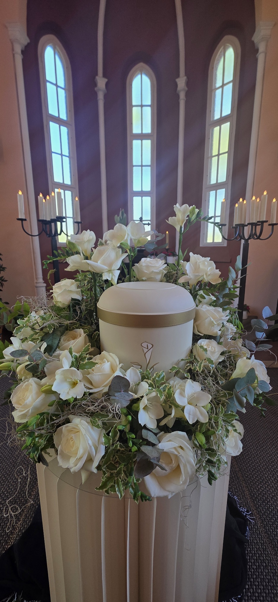 Urne mit weißem Rosenschmuck in der Trauerhalle
