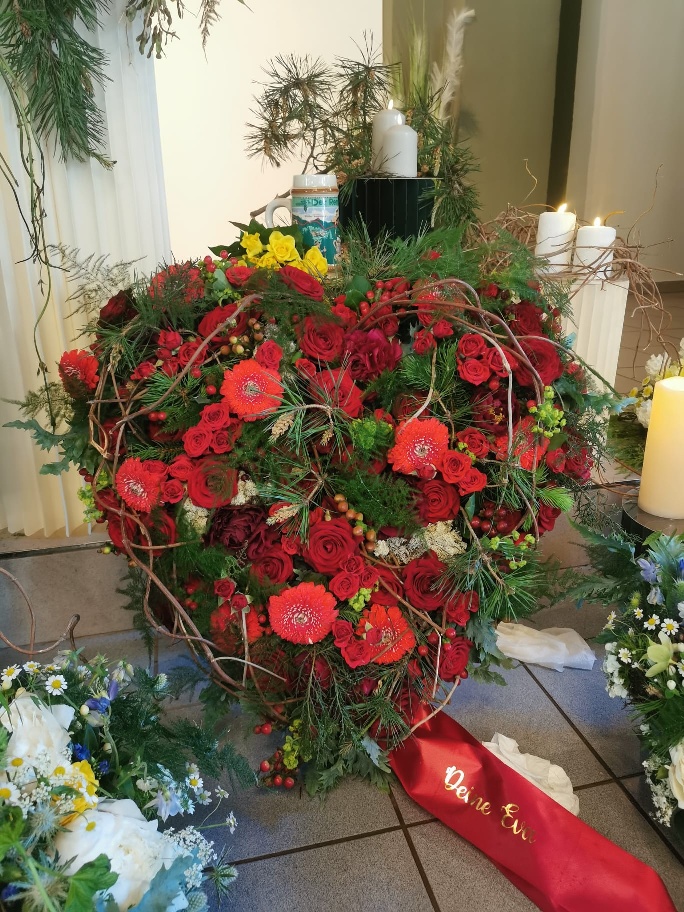 Herzgesteck aus roten Rosen mit Gedenkkerzen